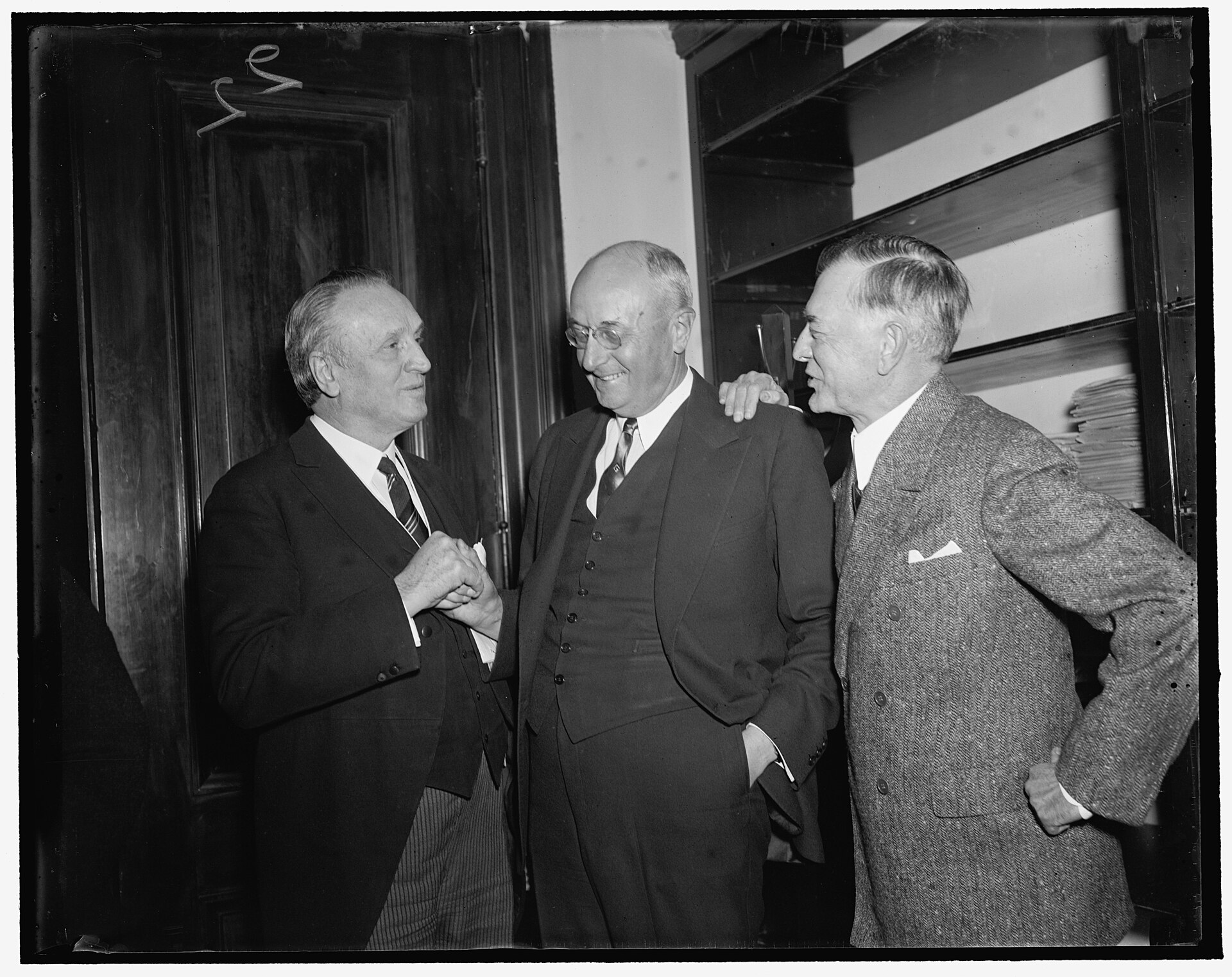 Homer Cummings stands between two senators at the Capitol, shaking hands with Henry Ashurst.